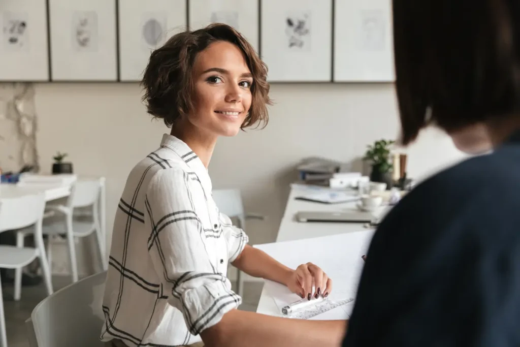Une jeune femme menant un entretien individuel -pour une entreprise dans le cadre des enjeux de la GEPP, tourne la tête à droite et regarde la caméra.