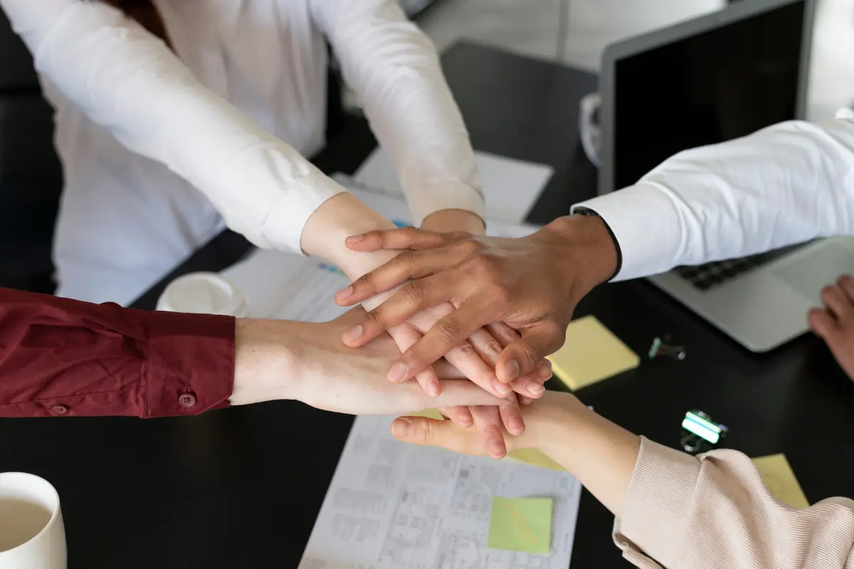 4 personnes empilent leur main au centre de la table, en signe de solidarité avant de commencer un atelier jeu du blason. Un moment de cohésion propice au développement de l'intelligence collective.