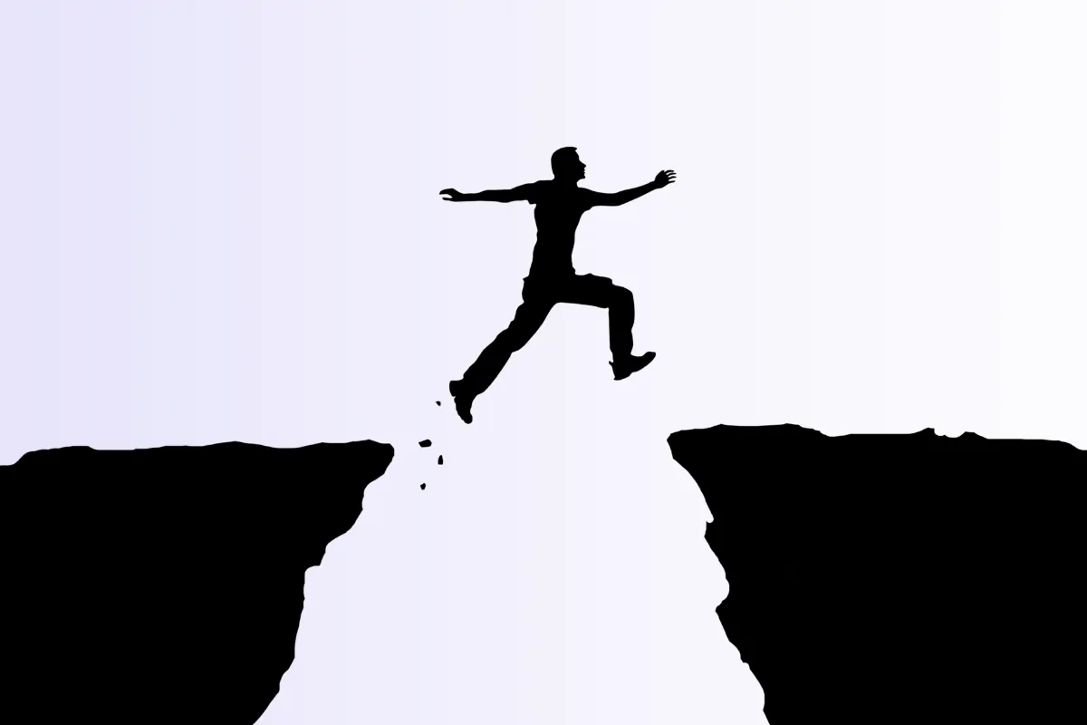 Deux terres séparées et une personne qui saute d'une terre à l'autre pour illustrer le fait de passer à l'action en créant son entreprise à l'aide du dispositif "Ici, je monte ma boîte Caen"