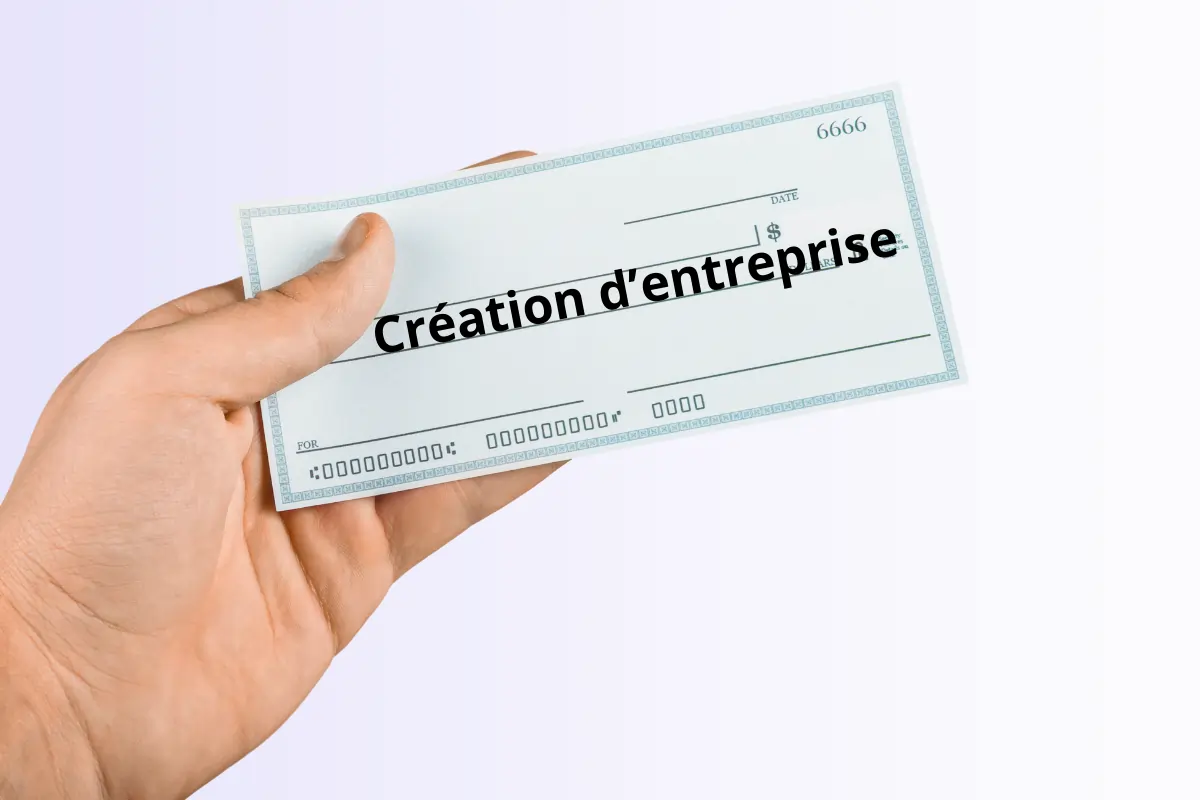 une main tenant un chèque avec inscrit "chèque création d'entreprise" dans le cadre du dispositif "Ici, je monte ma boîte Caen"