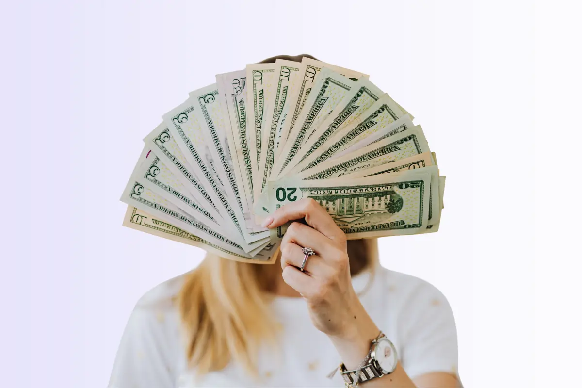 une femme qui tient des billets devant son visage pour illustrer le sujet de la rémunération en reclassement