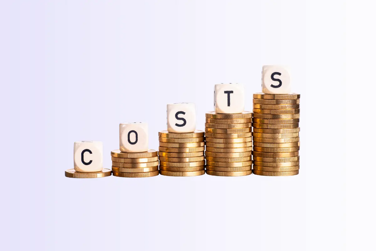 Des piles de pièces avec des dés formant un mot au dessus de chaque pile. Le mot est "costs" soit "les coûts" en anglais.