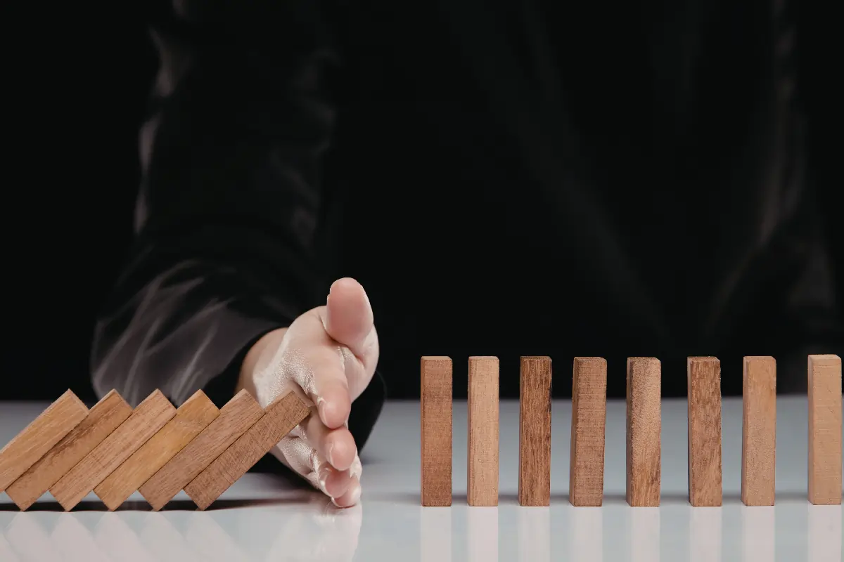 une personne qui arrête de sa main des dominos en chaine s'apprêtant à faire tomber les autres. La parfaite illustration qu'il vaut mieux prévenir que guérir quand on parle de conflit entre deux salariés